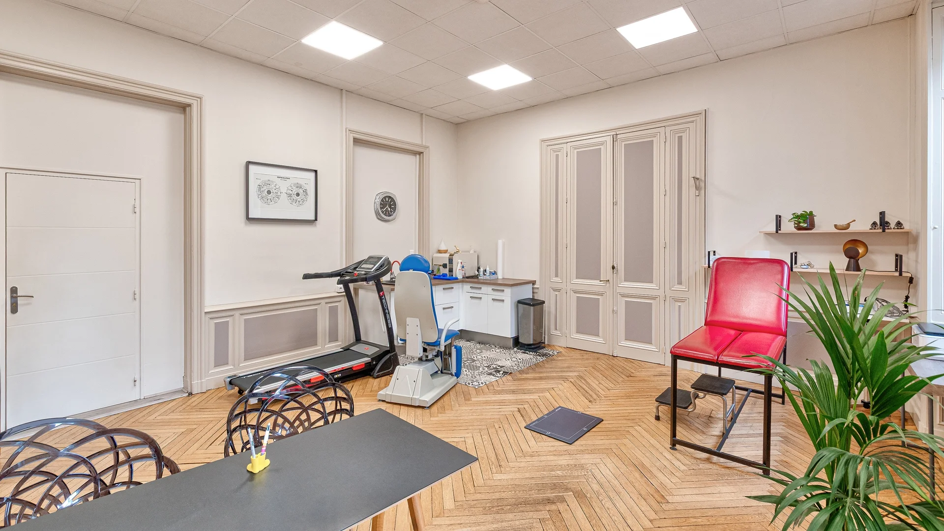 Cabinet de podologie moderne à Nantes Place Mellinet équipé d'un tapis de course pour analyse de la marche, parquet en point de Hongrie et matériel médical professionnel.