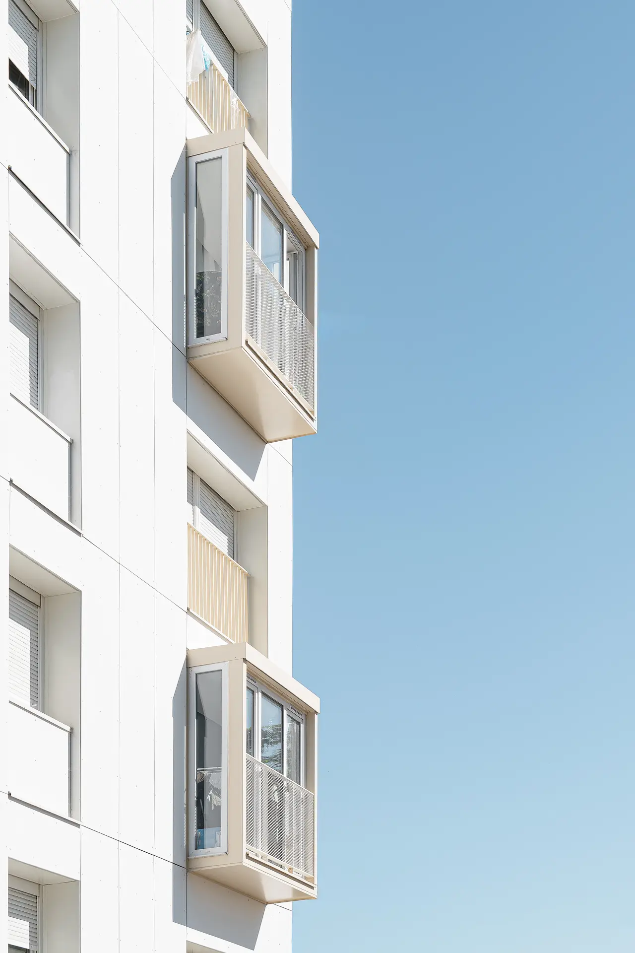 Photographie en contre-plongée des bow-windows modernes installés en façade d'un immeuble réhabilité par l'agence Jba à Nantes Bottière.