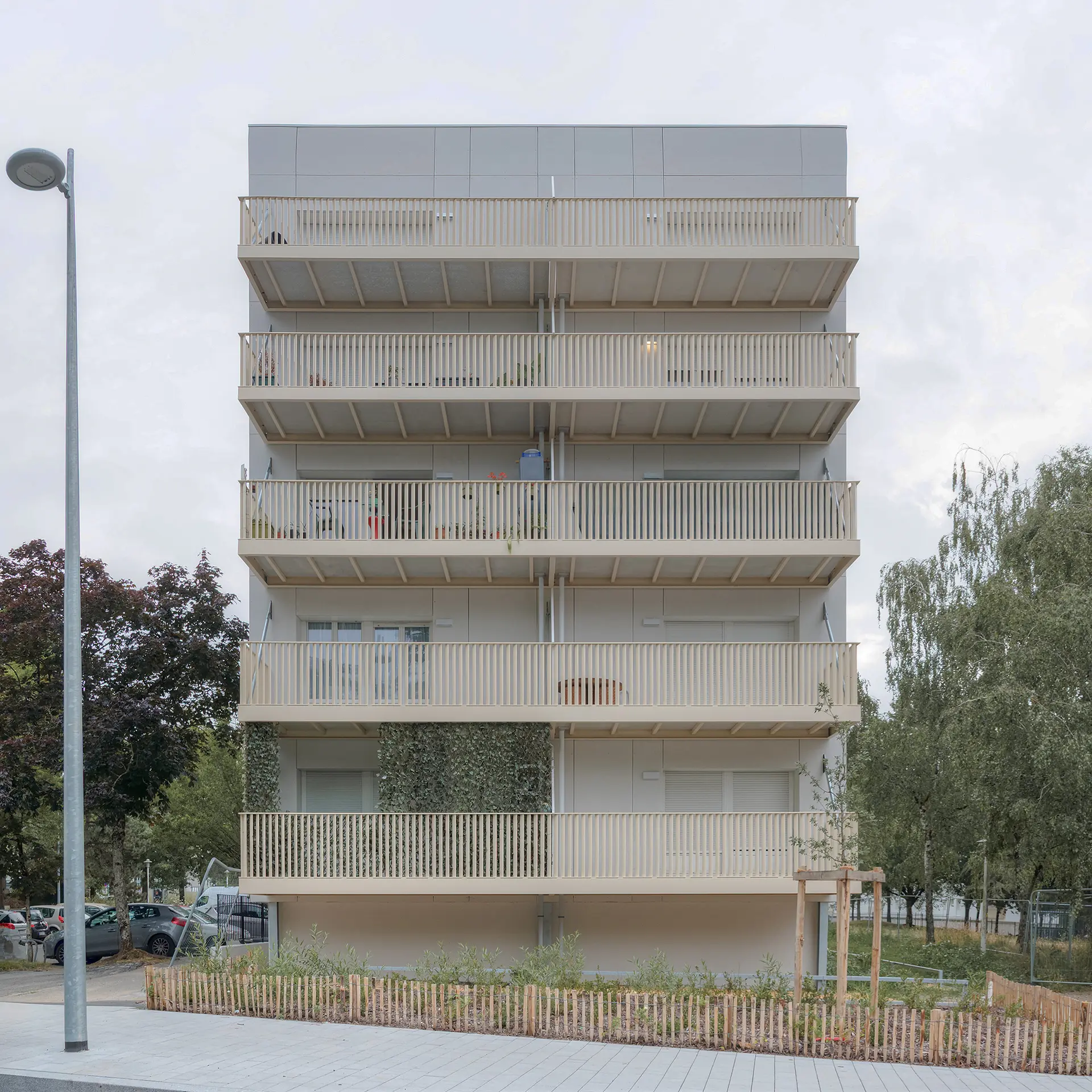 Vue de face des balcons en colonnes beige clair ajoutés sur la façade d'un bâtiment résidentiel rénové par l'agence Jba à Nantes.