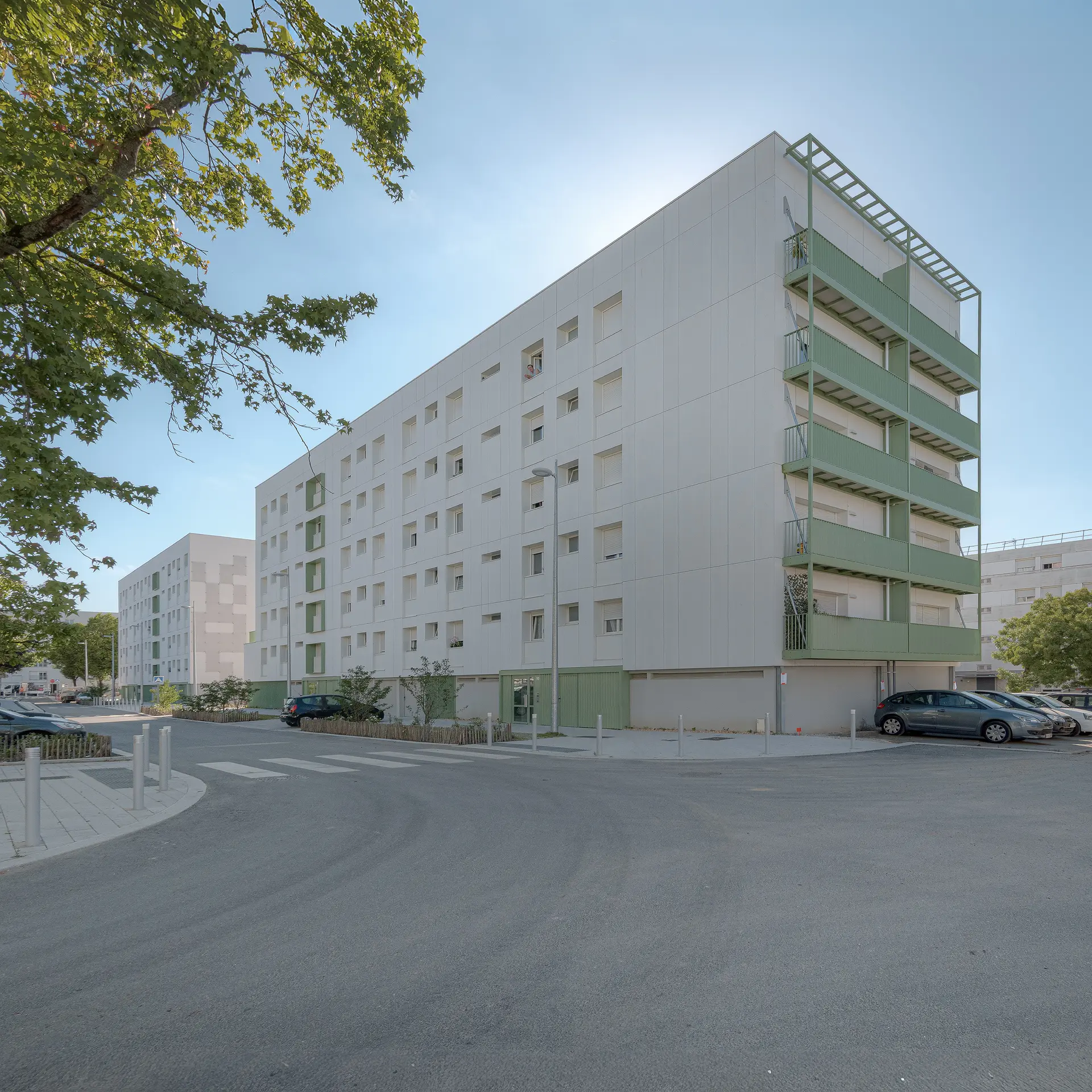 Prise de vue grand angle d'un ensemble immobilier réhabilité à la Bottière avec balcons suspendus verts et aménagement de voirie.