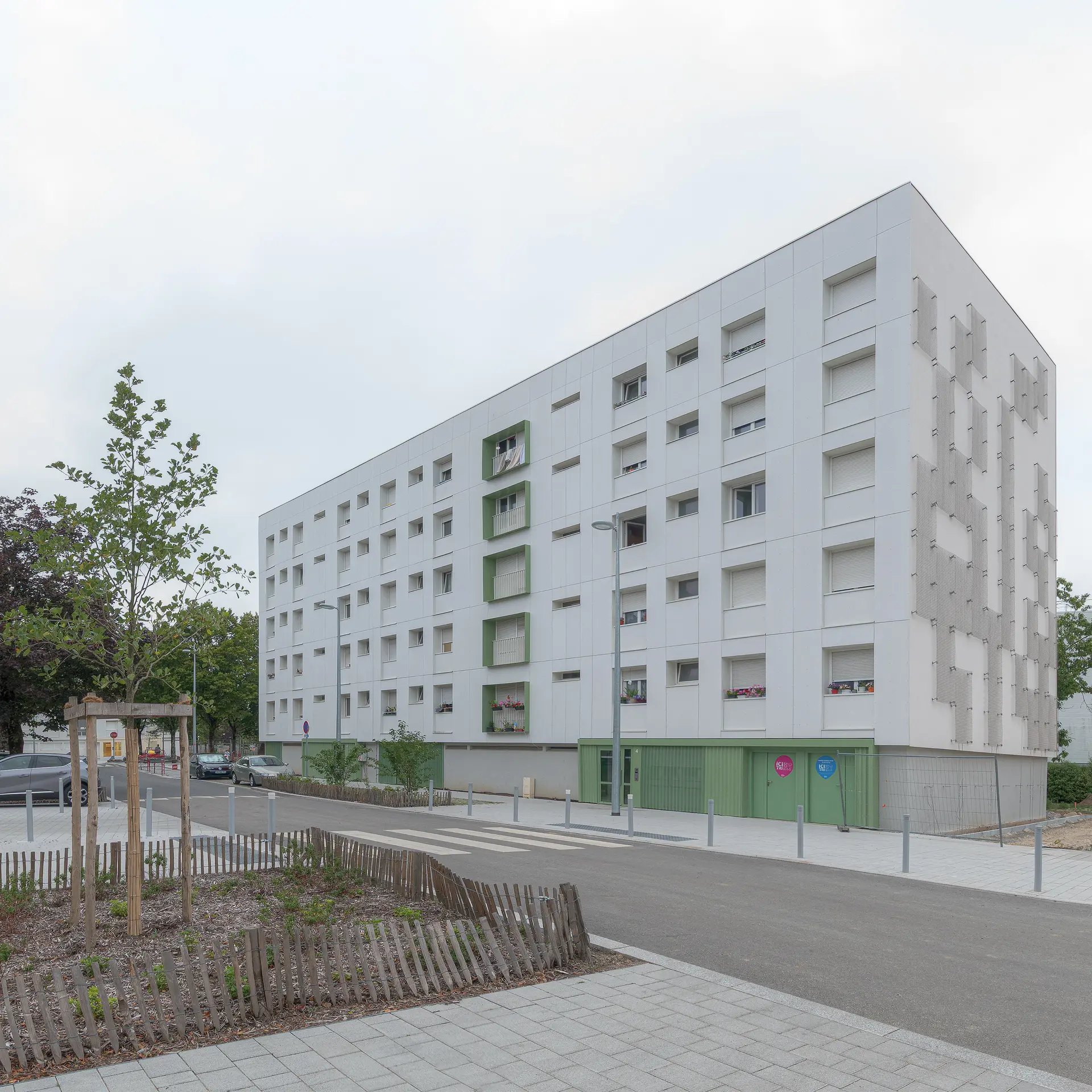 Vue perspective d'un immeuble réhabilité avec un habillage de façade texturé et un aménagement paysager au premier plan, agence Urbatera.