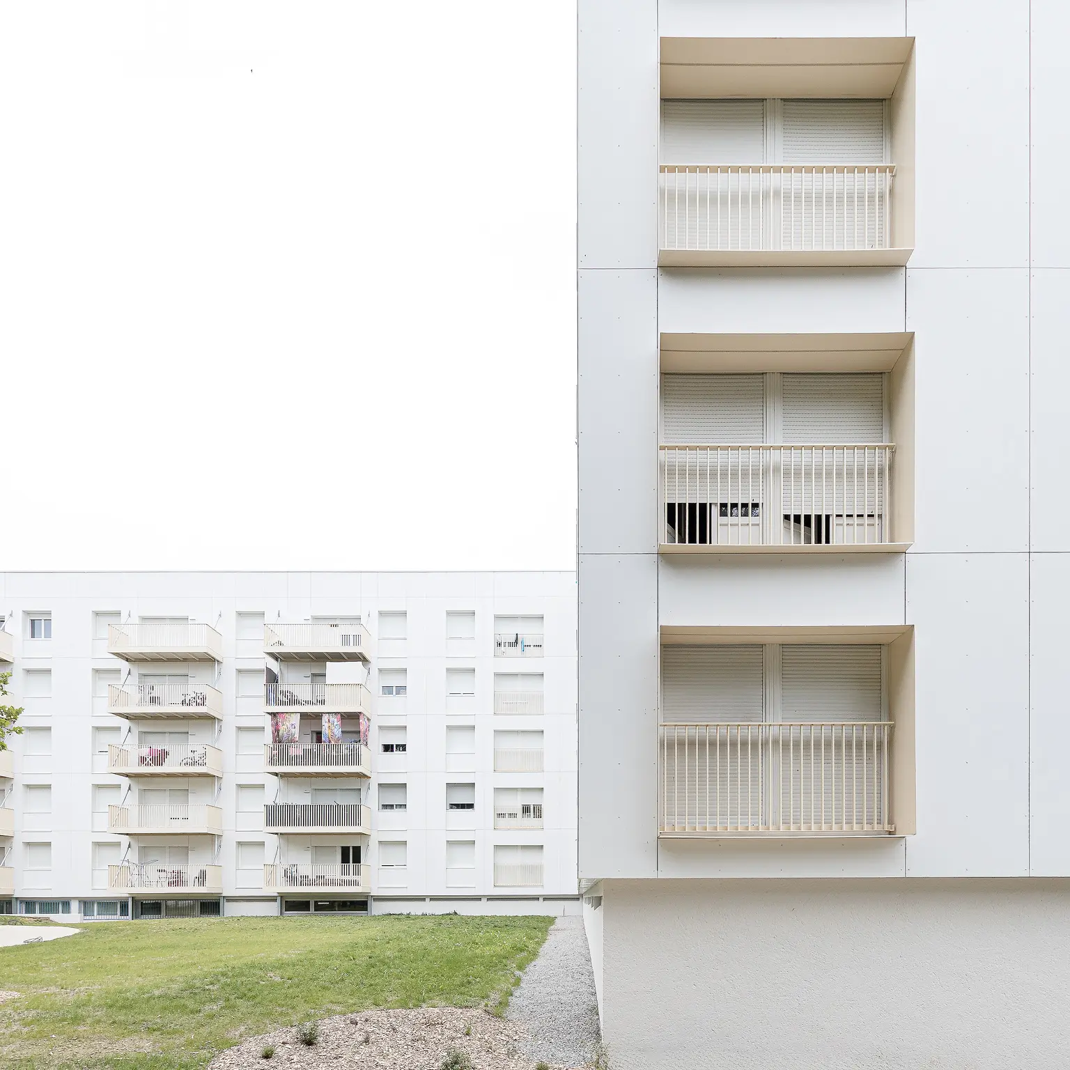 Photographie d'architecture épurée mettant en opposition le détail de loggias encadrées au premier plan et une façade à balcons filants en arrière-plan à Nantes.
