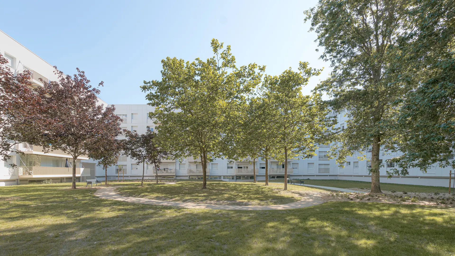Grand angle sur le parc intérieur paysager arboré reliant les différents bâtiments d'habitation réhabilités du quartier de la Bottière.